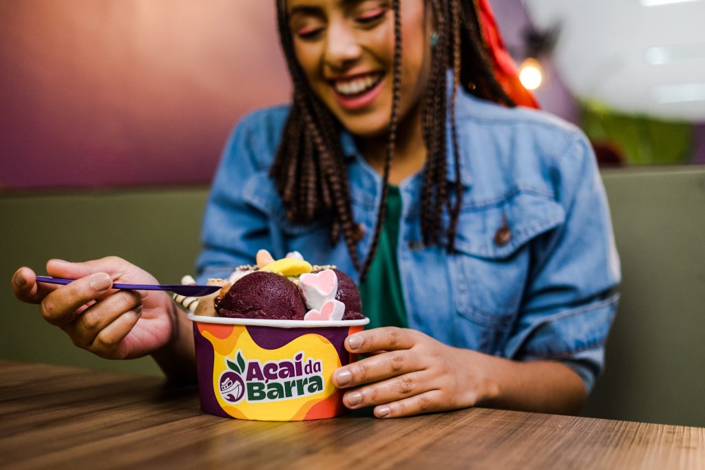 Menina sorridente tomando um sorvete em uma xícara de waffle em um café