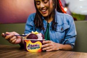 Menina sorridente tomando um sorvete em uma xícara de waffle em um café